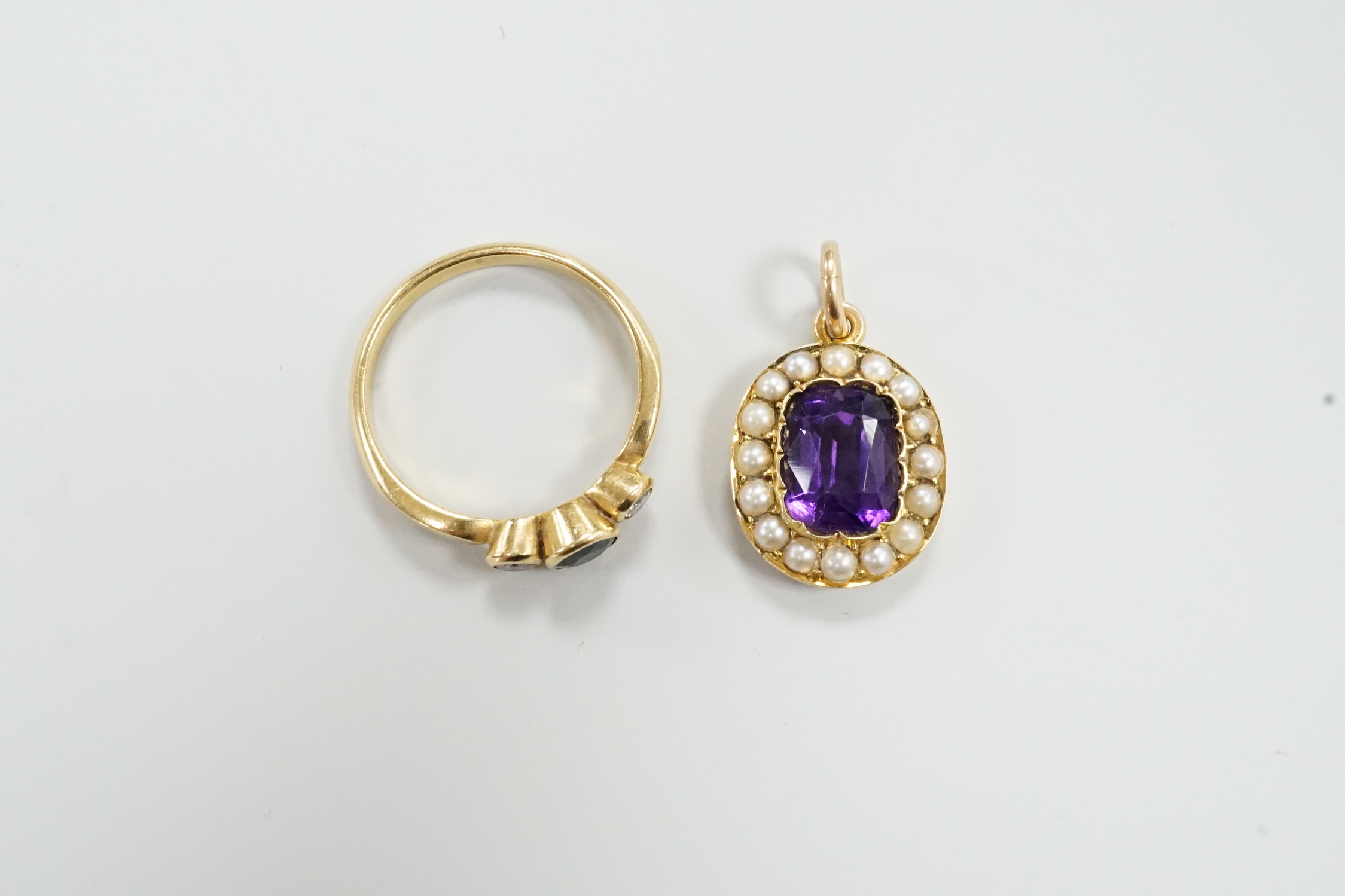 A yellow metal, sapphire and diamond set three stone ring, size O/P and a yellow metal, amethyst and seed pearl set pendant, gross weight 6.8 grams.